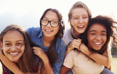 Vier unterschiedliche Mädchen, die in die Kamera lachen